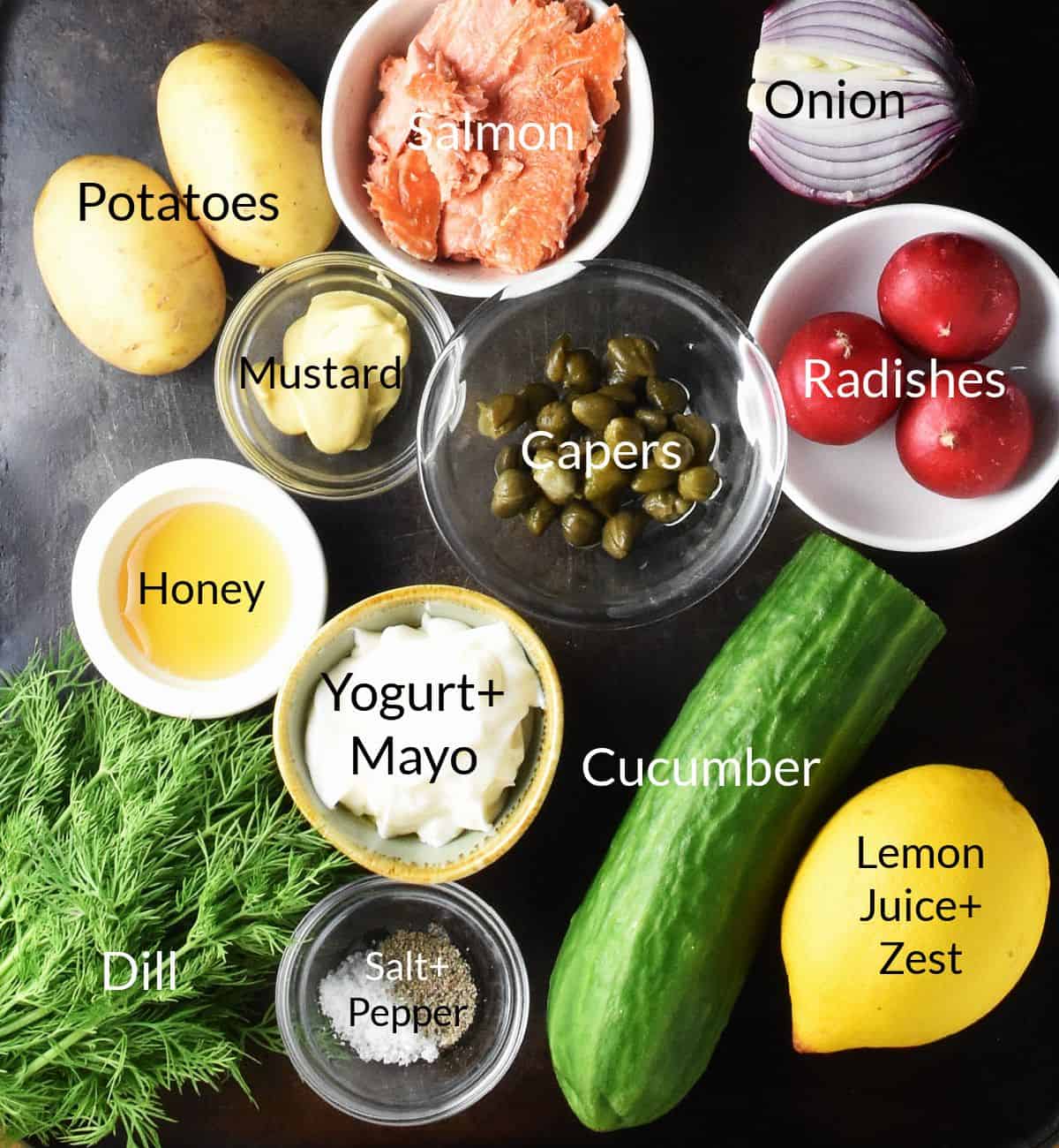 Top down view of ingredients for salmon and potato salad in individual dishes.