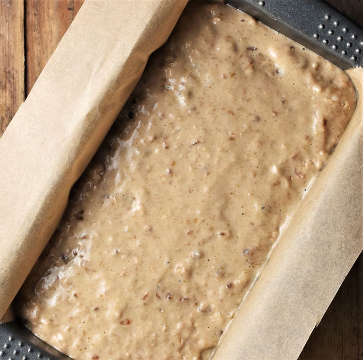 Banana dates bread batter in loaf pan lined with parchment.