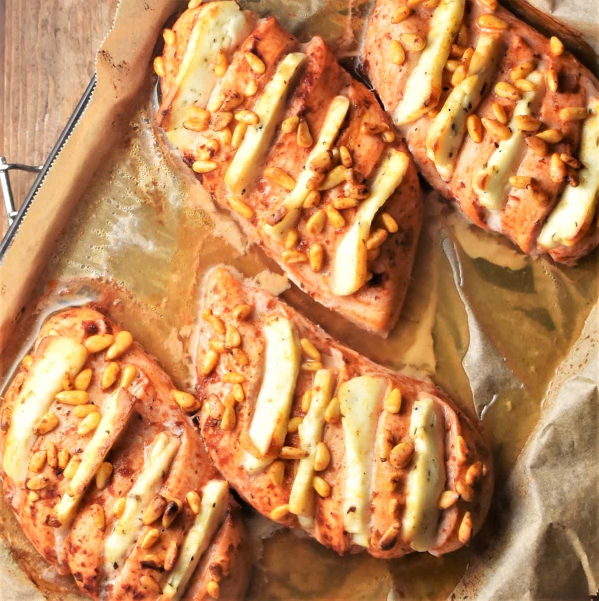 4 baked hasselback chicken breasts with halloumi on top of baking sheet.
