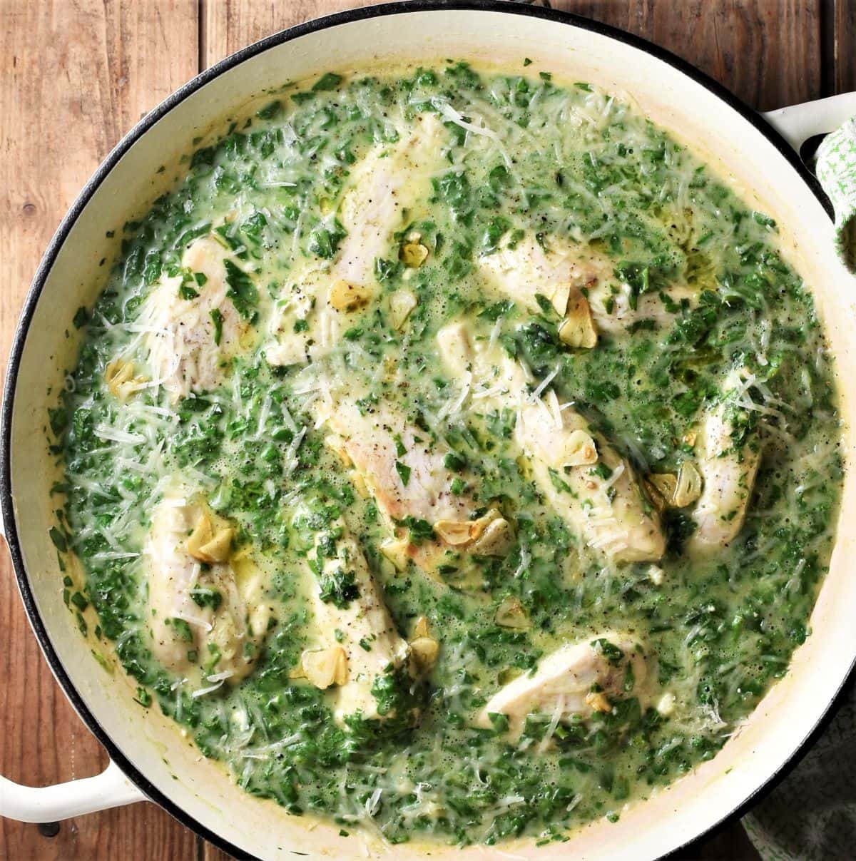 Chicken breast in creamy spinach sauce in large shallow pan.