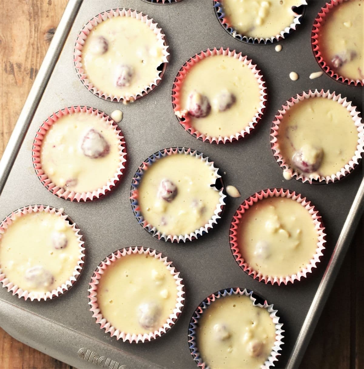 Muffin batter in paper cases in muffin pan.