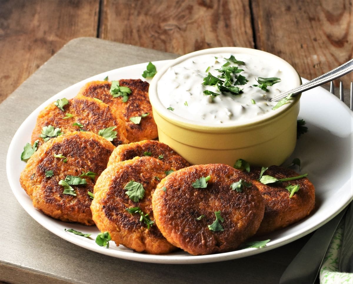 Side view of sweet potato fritters with herbs and yogurt dip.