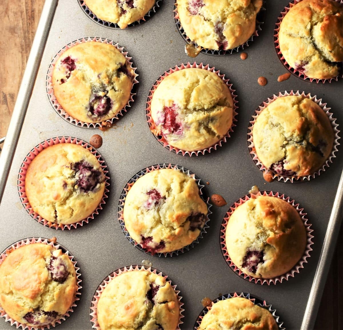 Top down view of 12 raspberry muffins inside muffin tin.