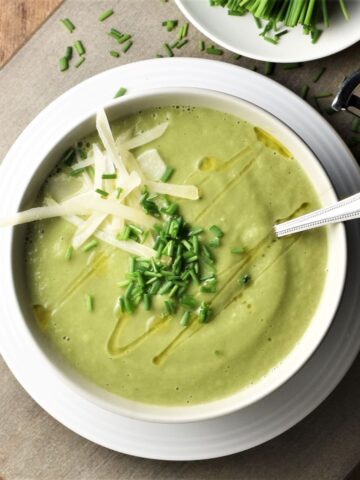 Top down view of creamy fennel soup in white bowl with spoon.