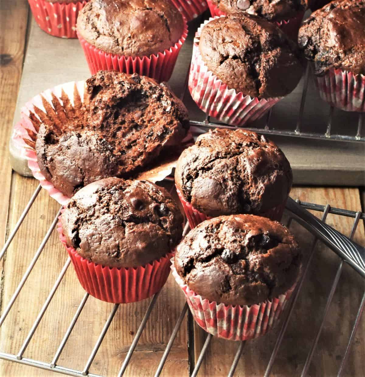 Chocolate muffins in red paper liners on top of rack and board.