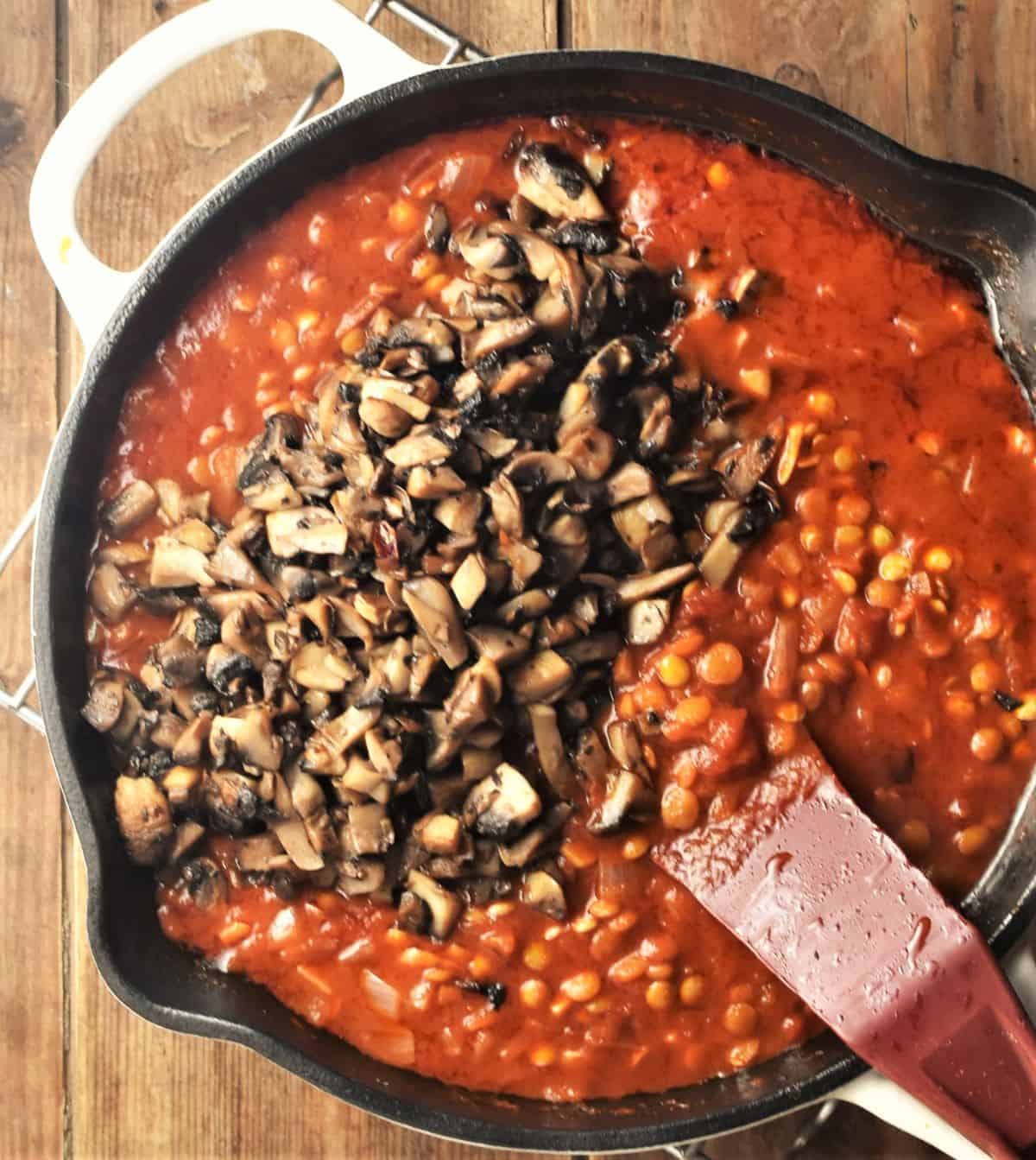 Lentil sauce with tomatoes and chopped mushrooms in cast iron skillet.