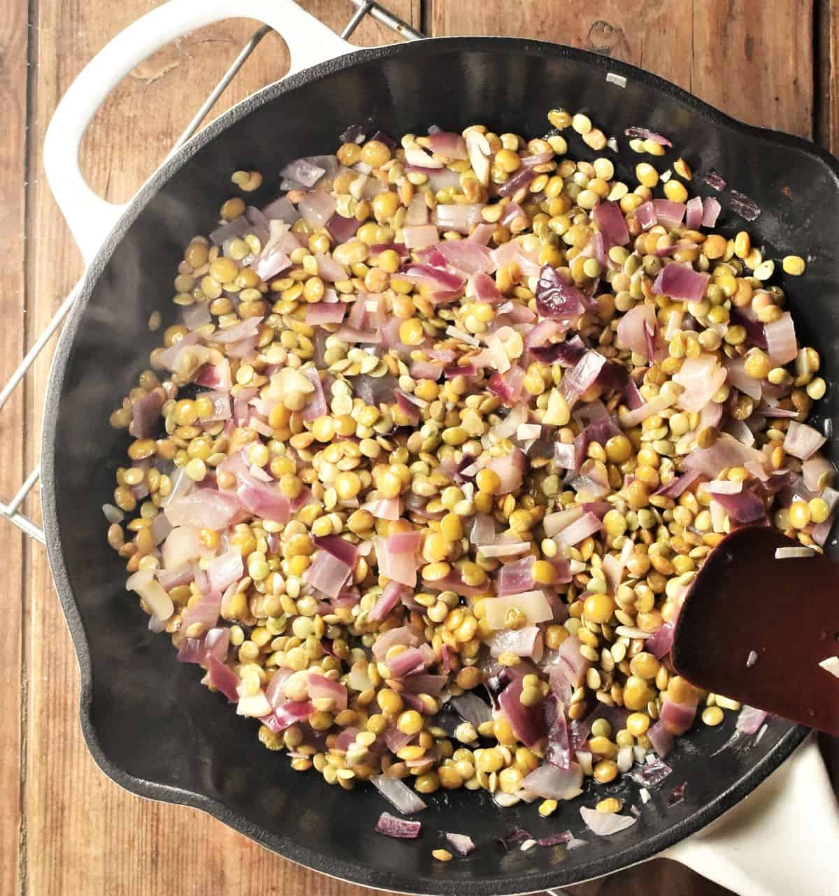 Cooking onion and green lentils in cast iron skillet.