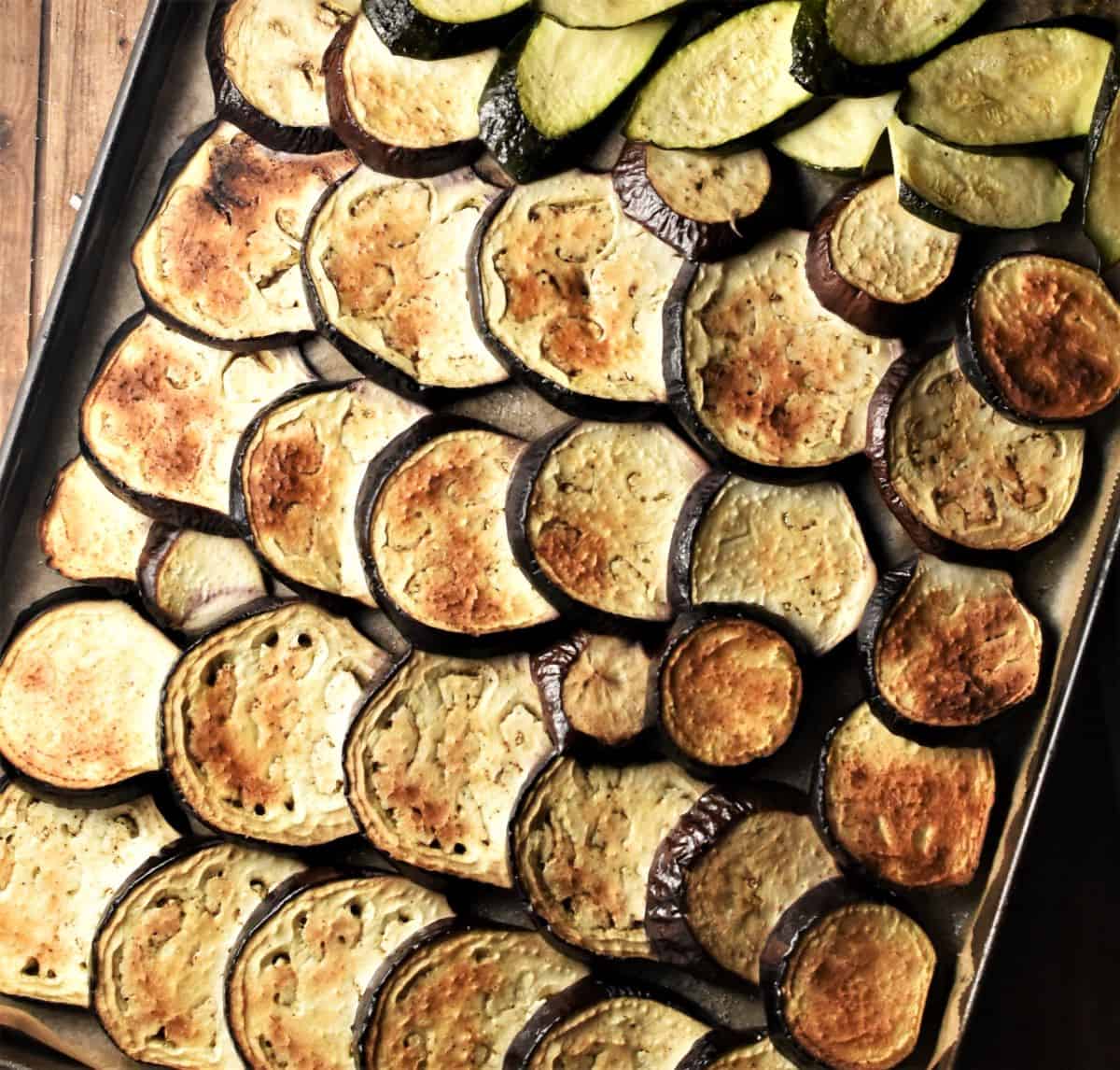 Lightly browned slices of eggplant and zucchini on top of baking sheet.