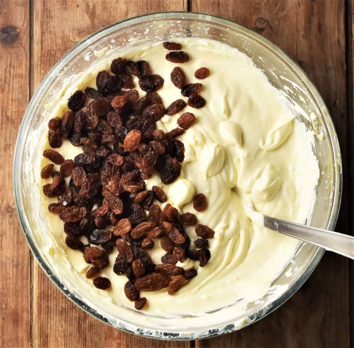 Folding raisins into cheesecake batter in mixing bowl.