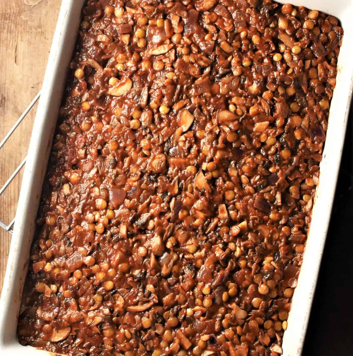 Assembling vegetarian moussaka by adding layer of lentil-and-mushroom mixture.