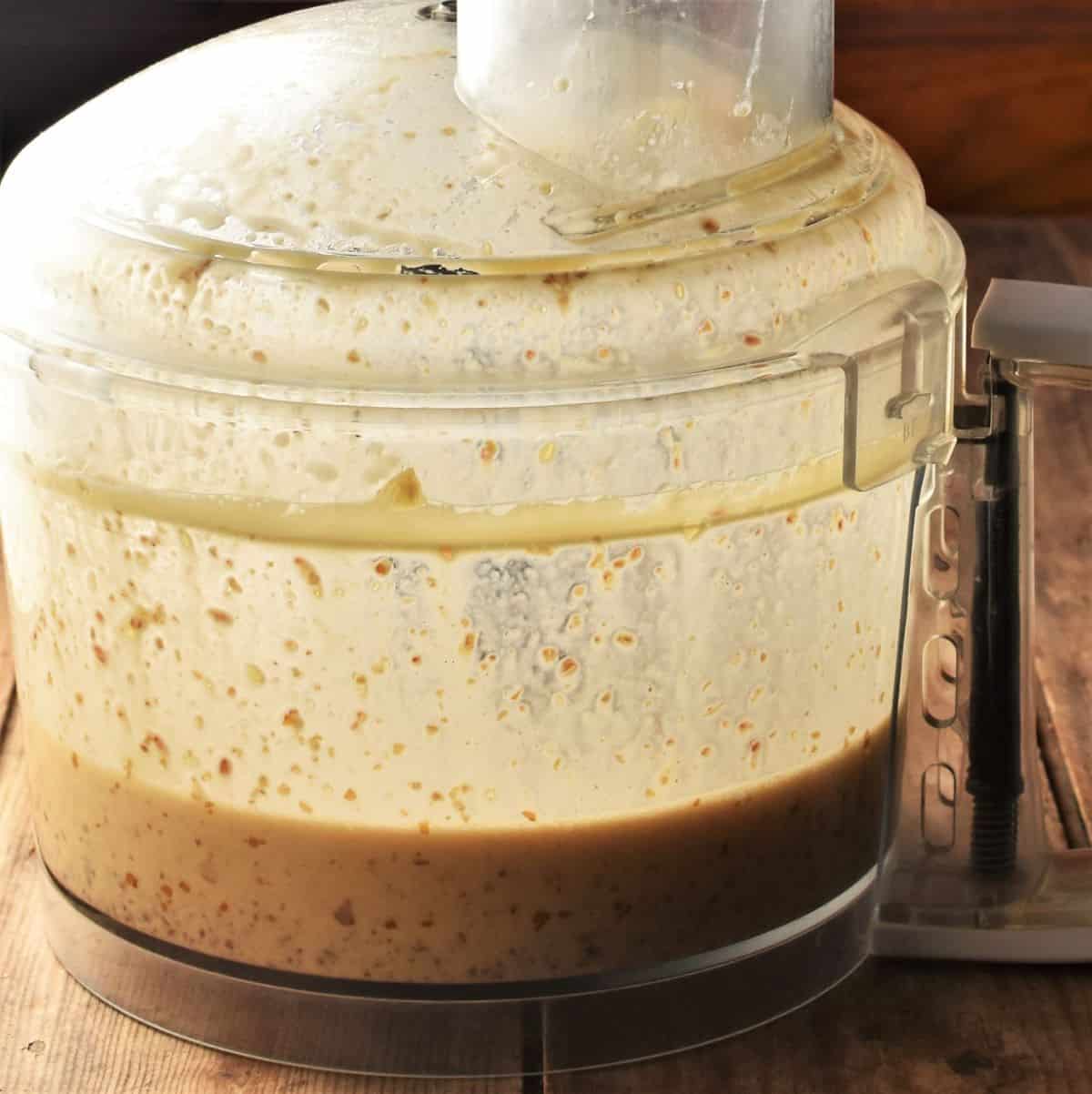 Side view of food processor bowl with wet mixture for muffins.