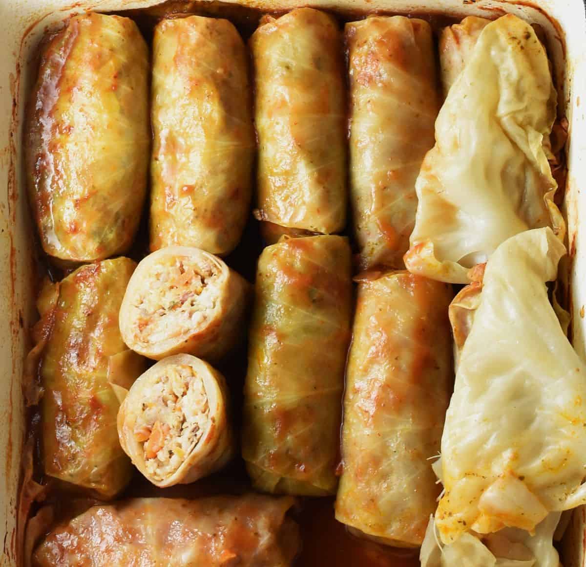 Top down view of sauerkraut stuffed cabbage rolls in tomato sauce with cabbage leaves.