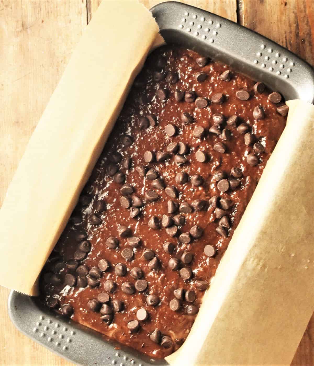 Top down view of banana chocolate cake batter with chocolate chips in loaf pan.