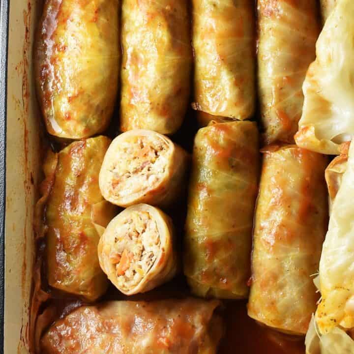 Top down view of sauerkraut cabbage rolls with tomato sauce in casserole dish.