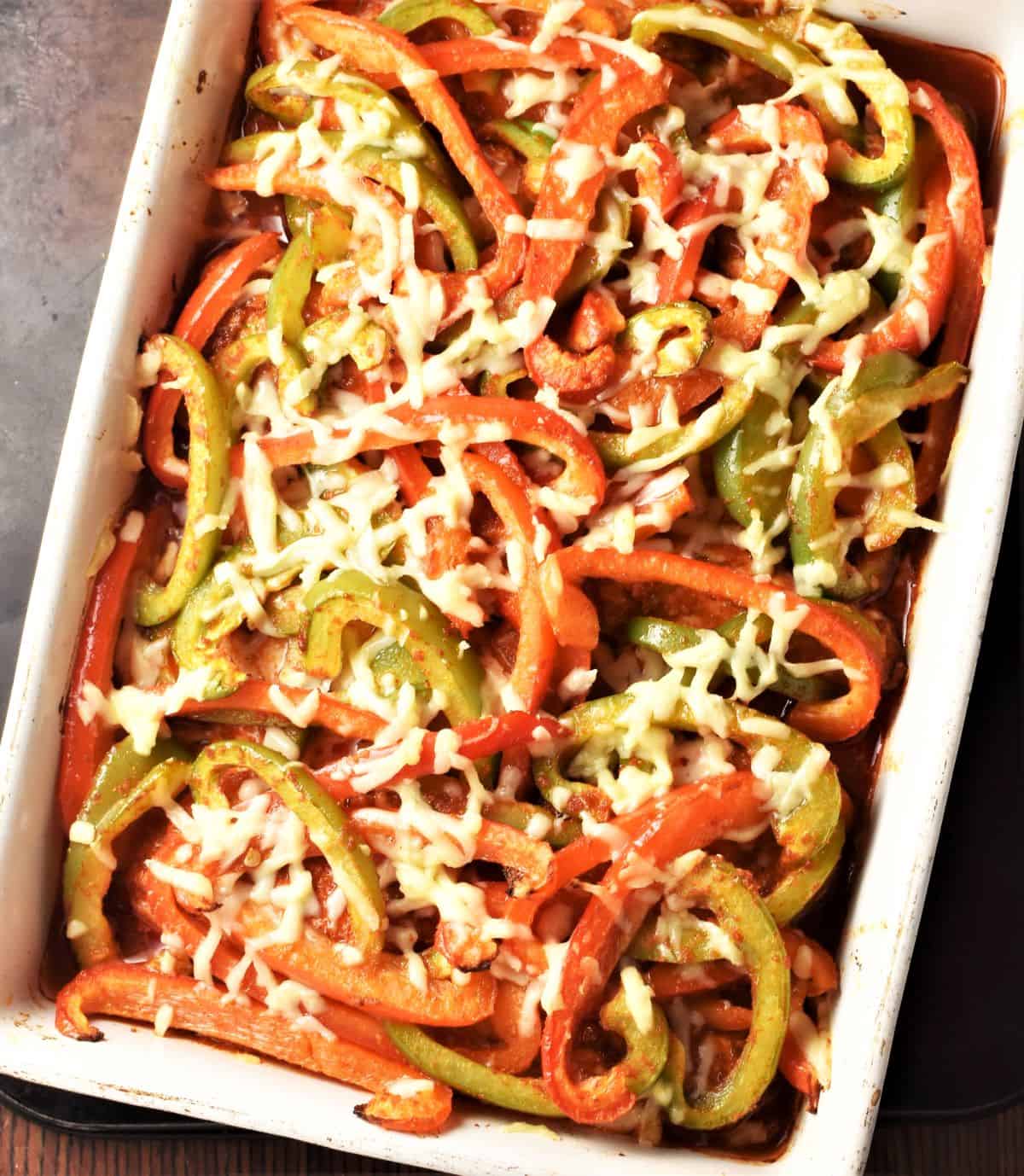 Top down view of chicken fajita bake with peppers and cheese in rectangular dish.
