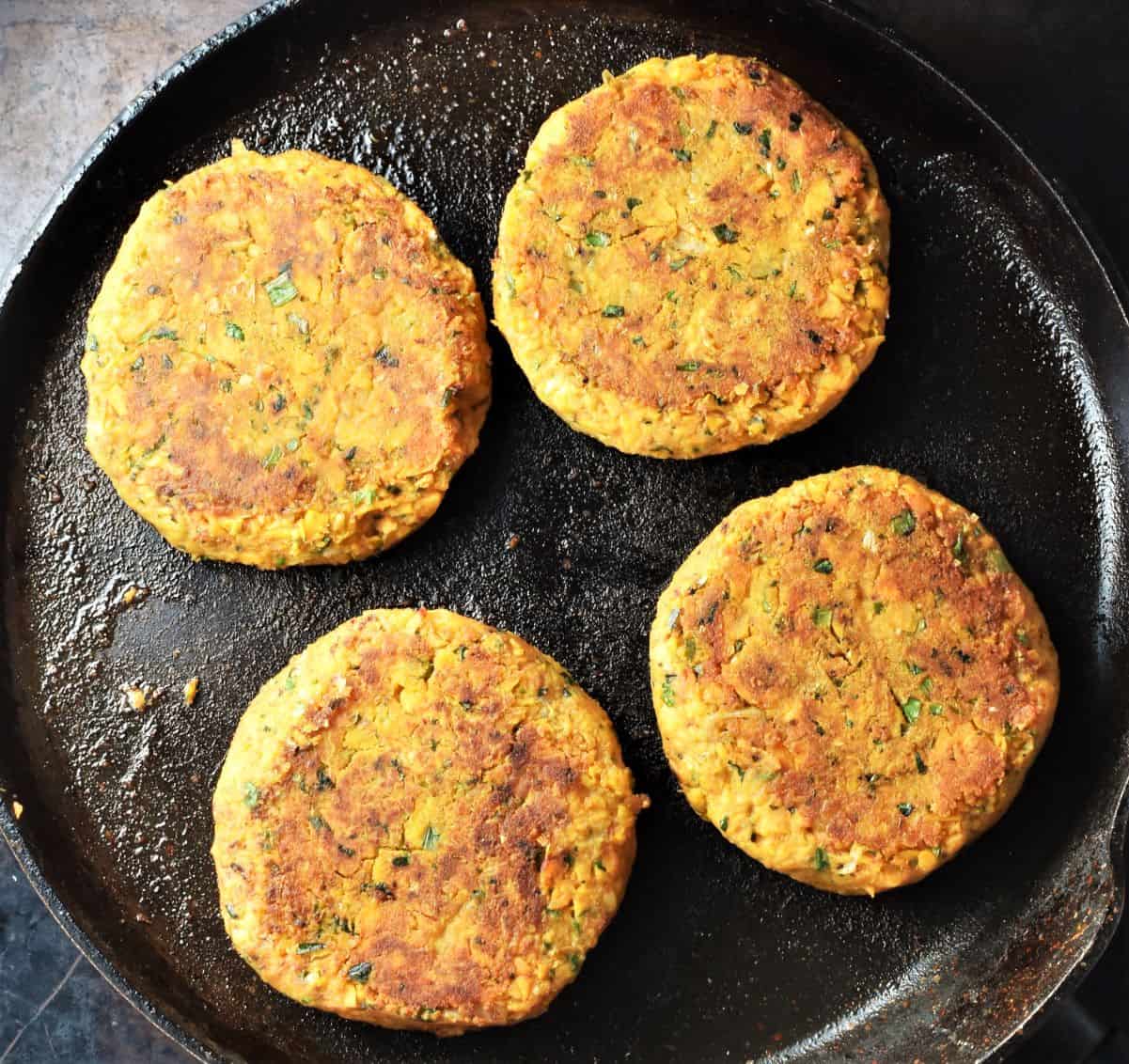 Frying 4 sweet potato burgers in large pan.