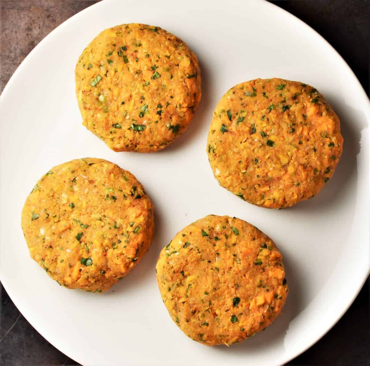 Forming 4 veggie burgers on top of white plate.