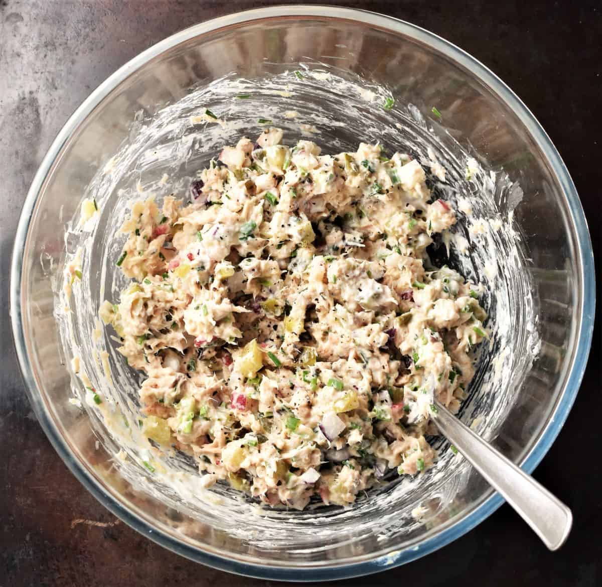 Salmon salad sandwich filling mixture in large bowl with spoon.