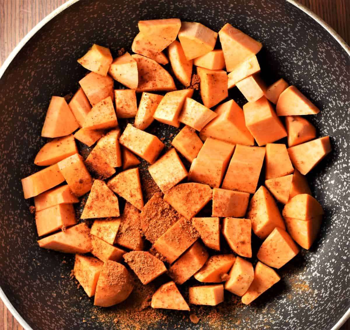 Sweet potato cubes with spices in large pan.