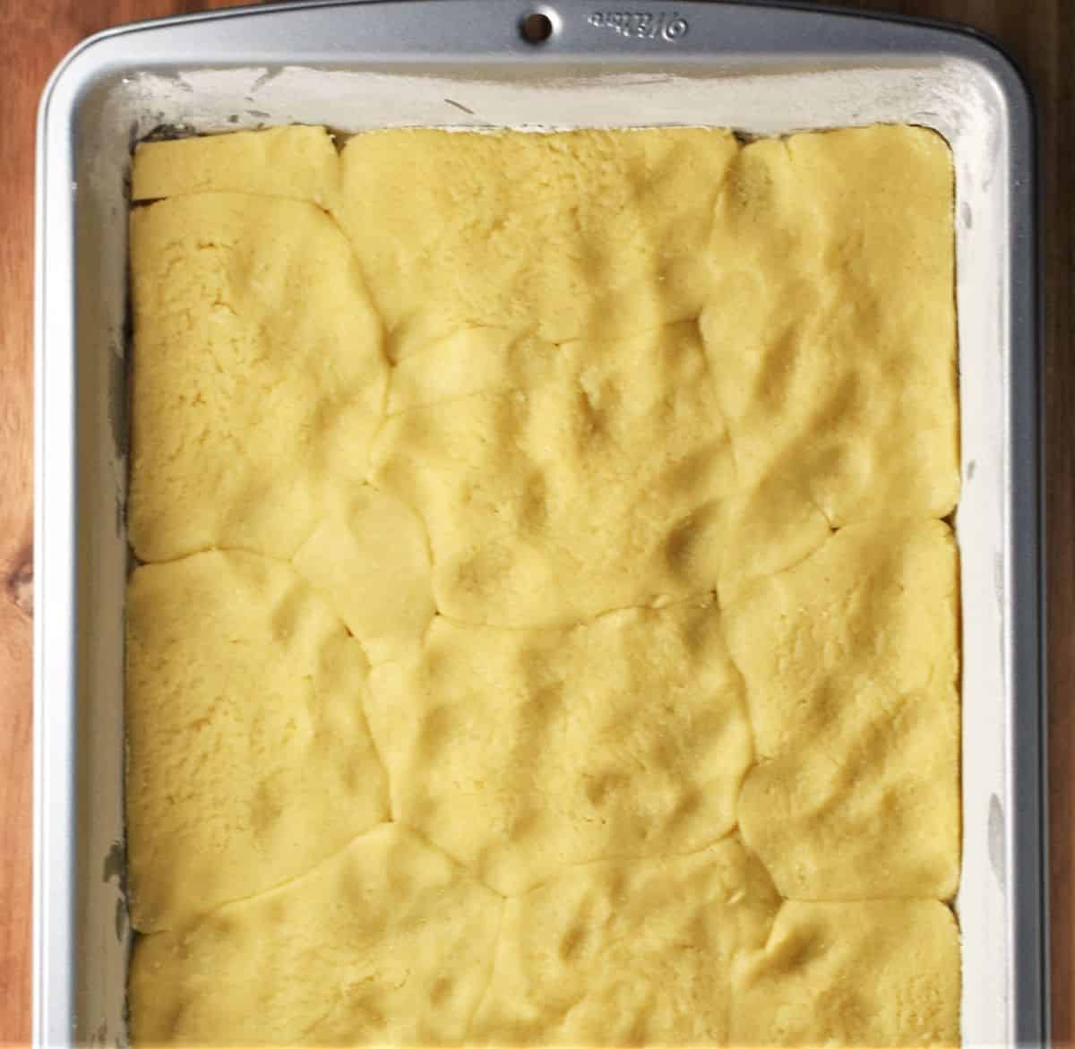 Assembling szarlotka recipe in rectangular pan.
