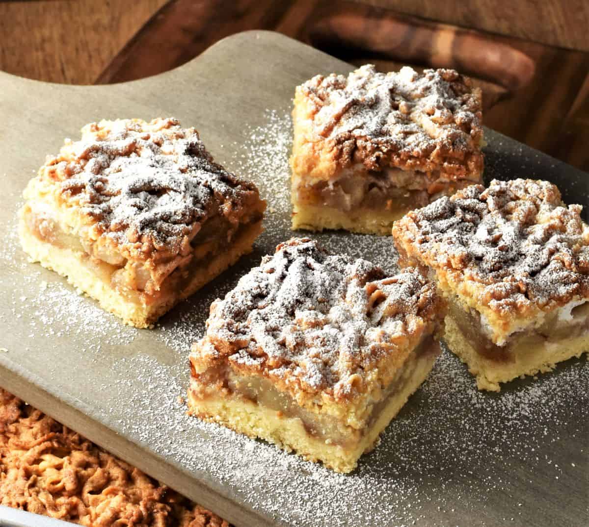 Side view of 4 apple cake slices on top of grey board.