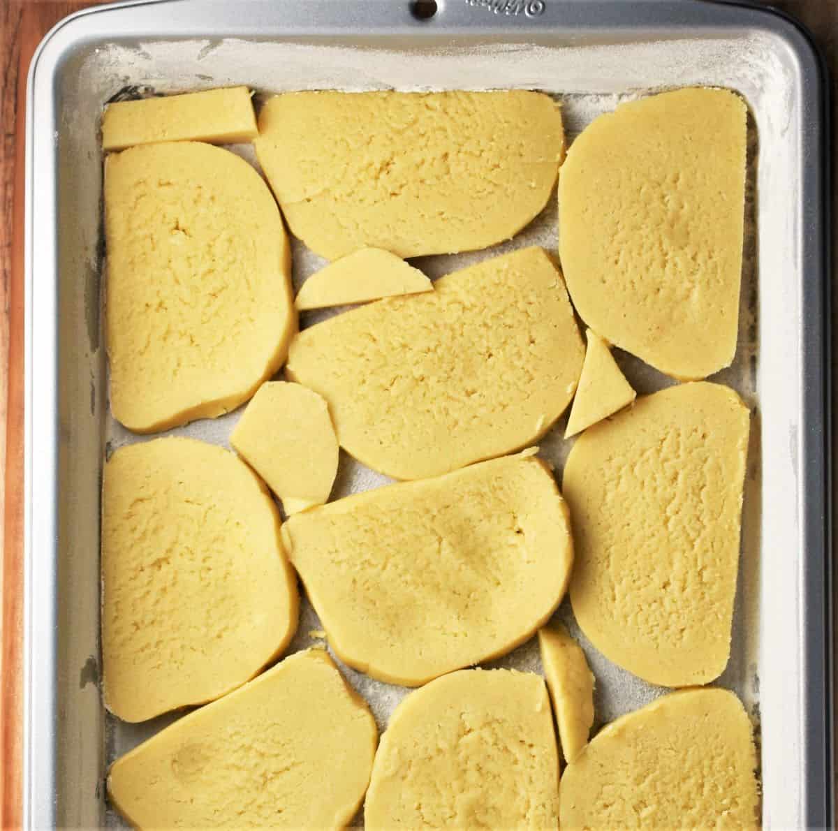 Slices of dough at the bottom of rectangular pan.