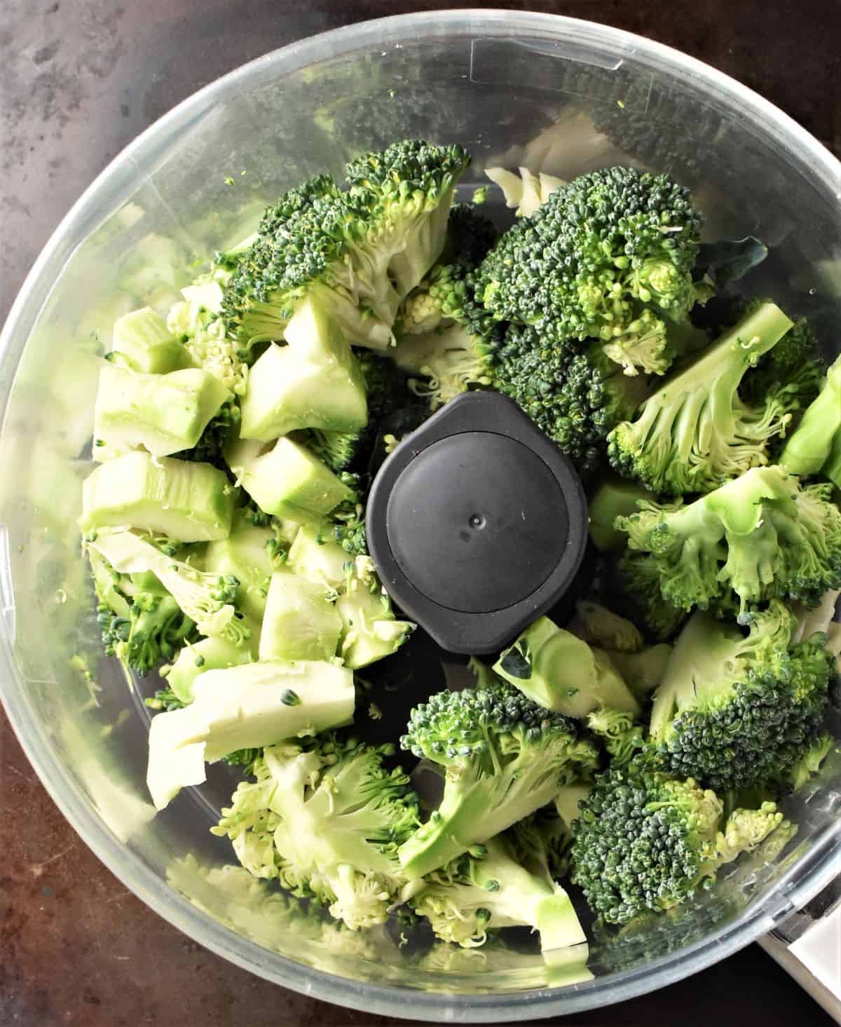 Chunks of raw broccoli in blender bowl.