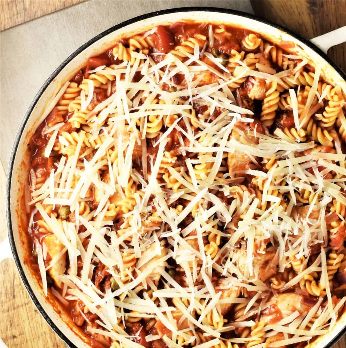 Chicken pasta bake with grated cheese in large shallow dish.