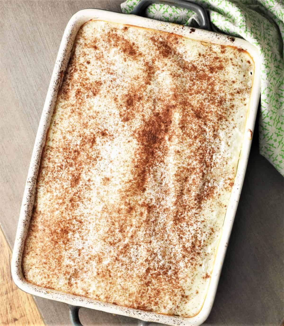 Top down view of Polish rice and apples pudding with cinnamon in rectangular dish.