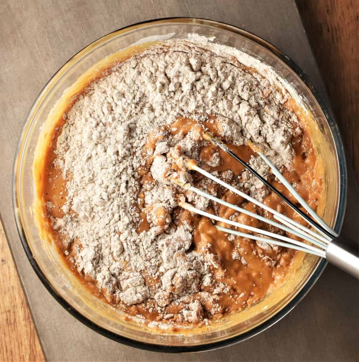 Whisking ingredients for pumpkin cake batter in bowl.