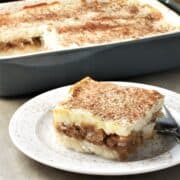 Side view of rice with apples slice on top of white plate.