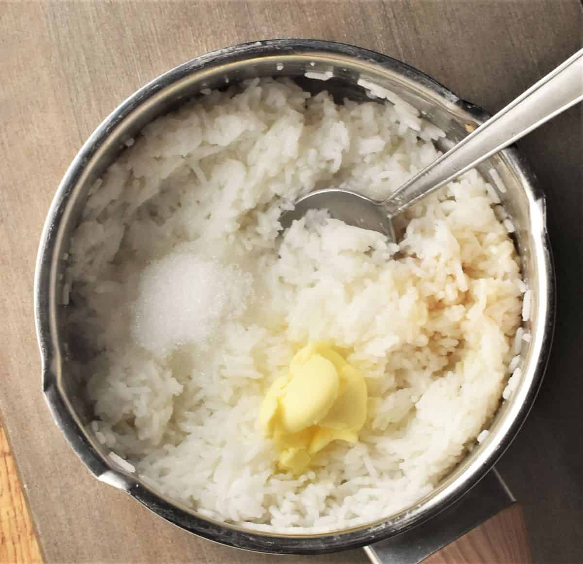 Cooked rice with butter in pot with spoon.