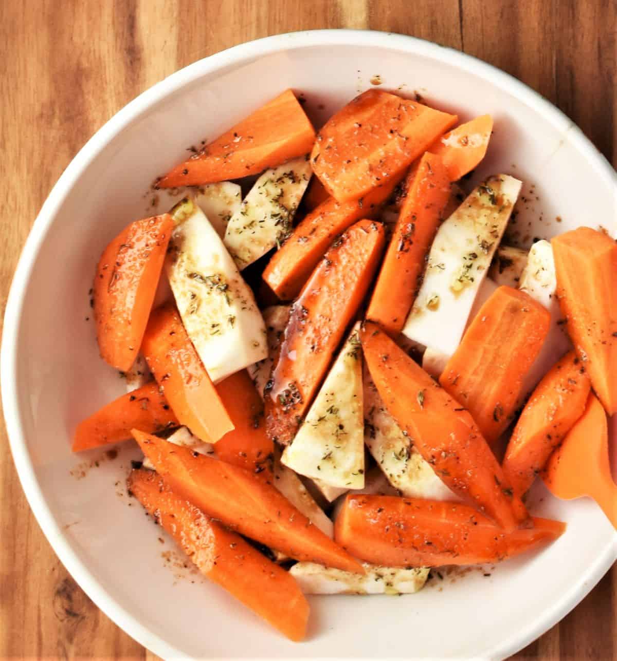 Coating peeled chopped root vegetables in balsamic mixture.