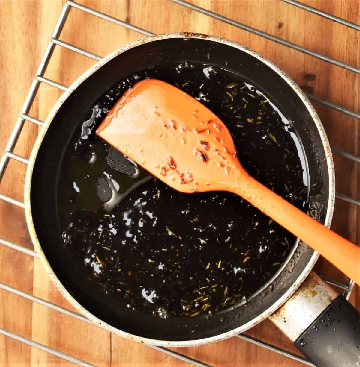 Making balsamic glaze in small pan with orange spatula.