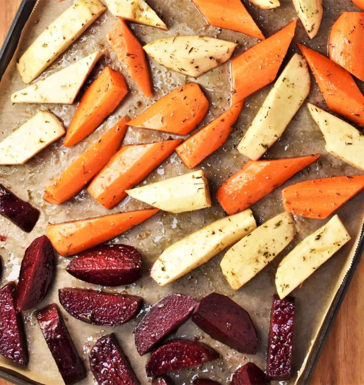Pieces of root vegetables on top of parchment ready for roasting.