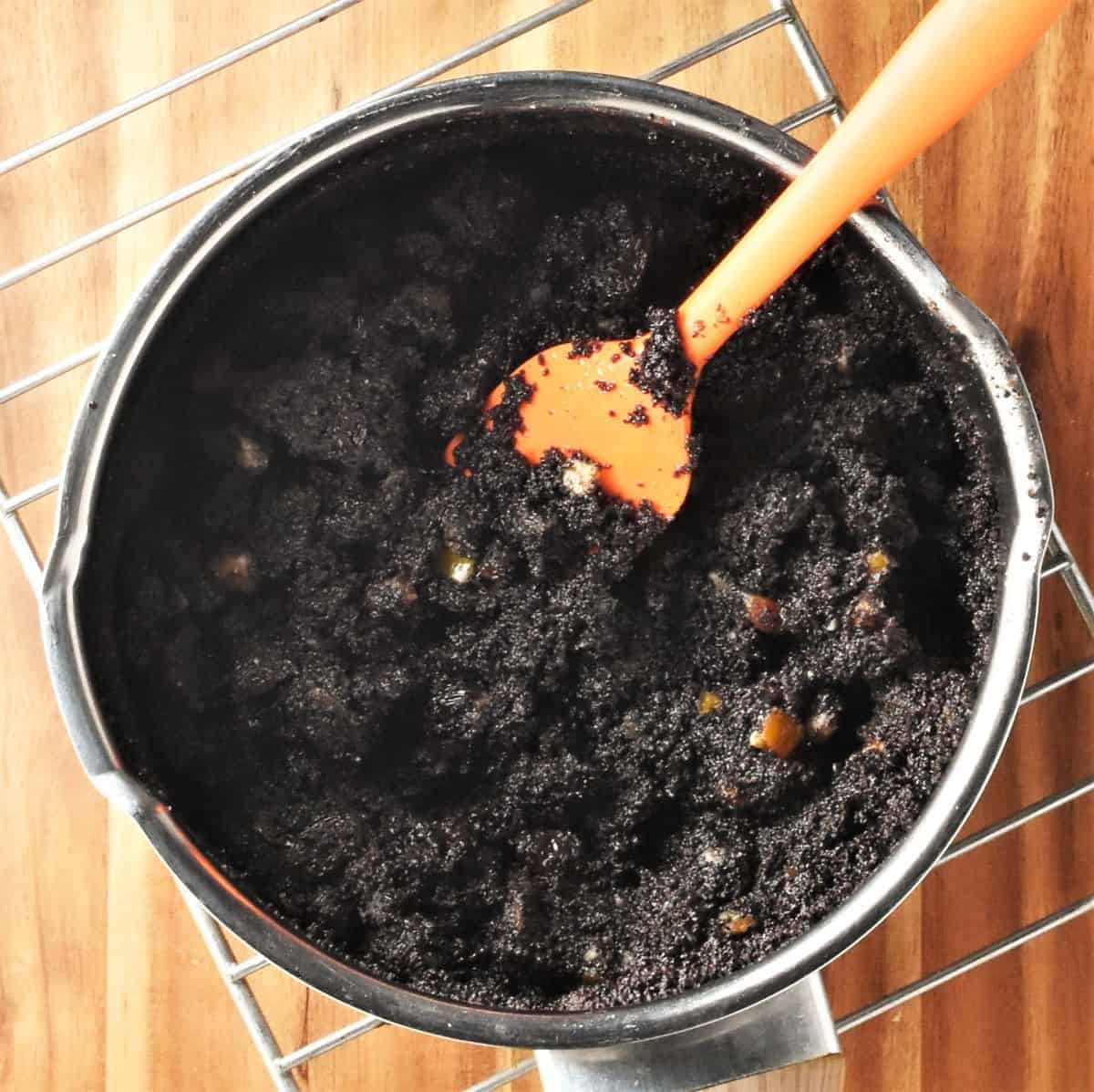 Poppy seed cake filling mixture in pot with orange spoon.
