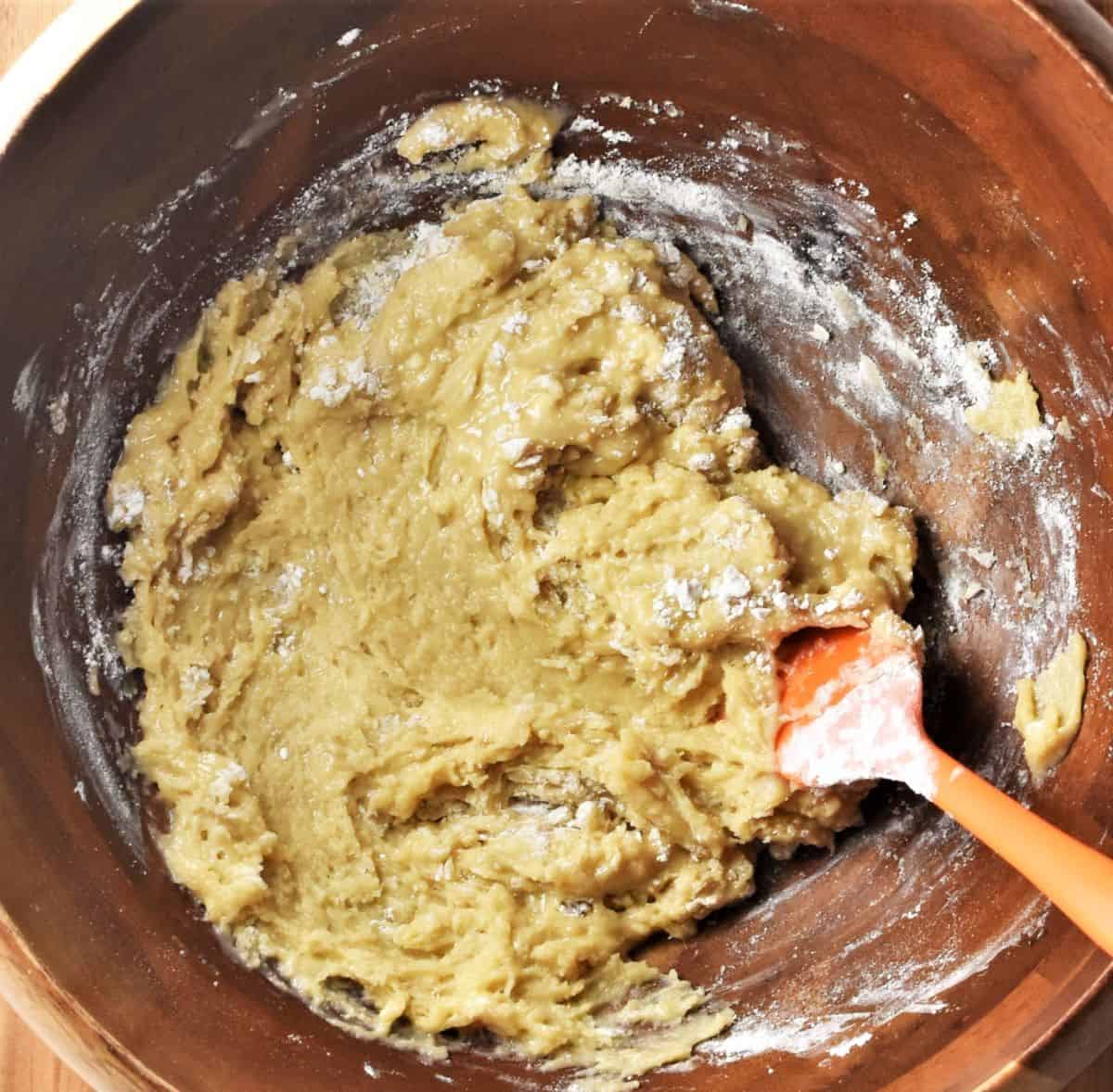 Stirring poppy seed cake dough ingredients in brown bowl.