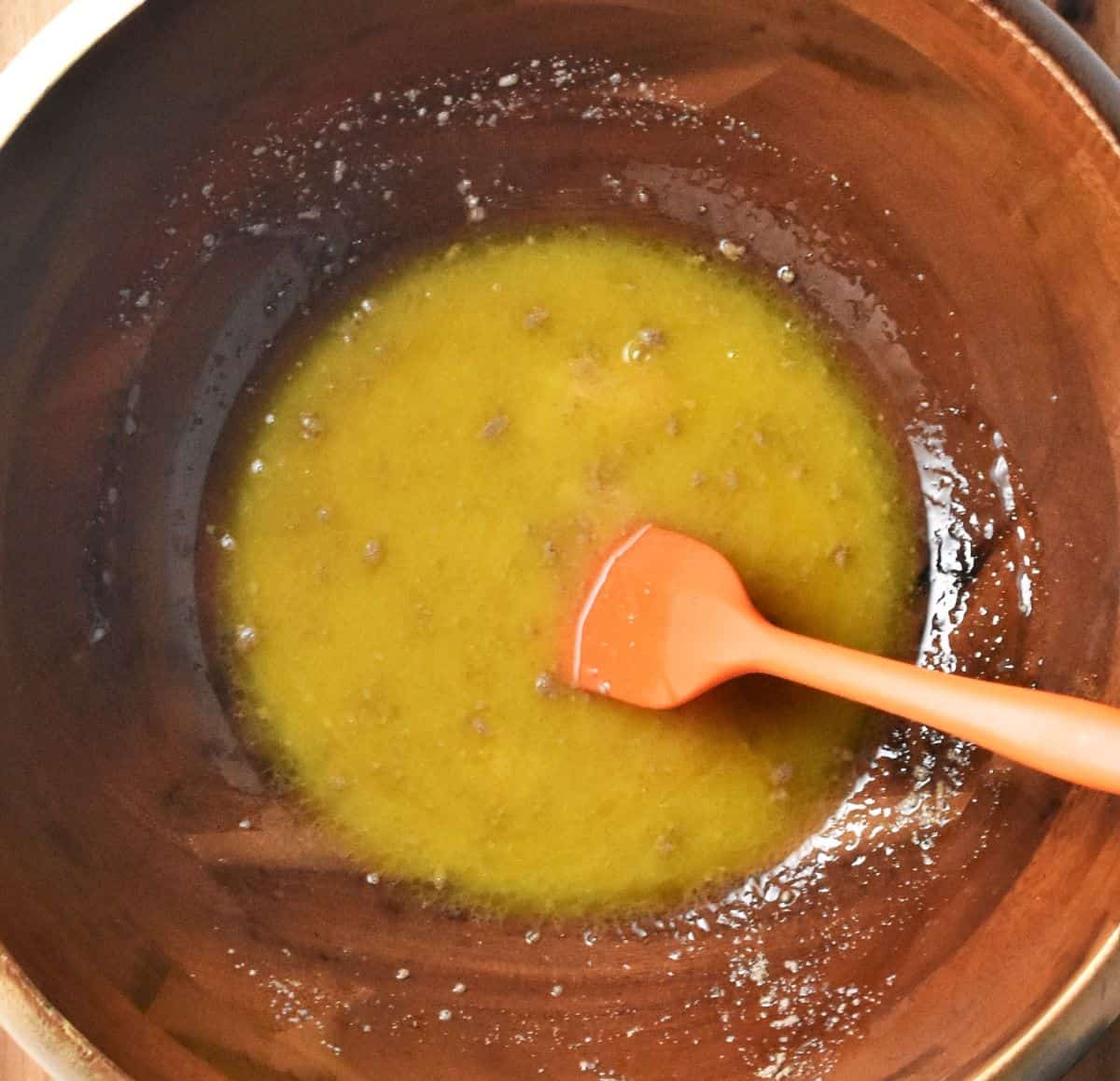 Yeast and milk mixture for cake in large bowl with orange spatula.