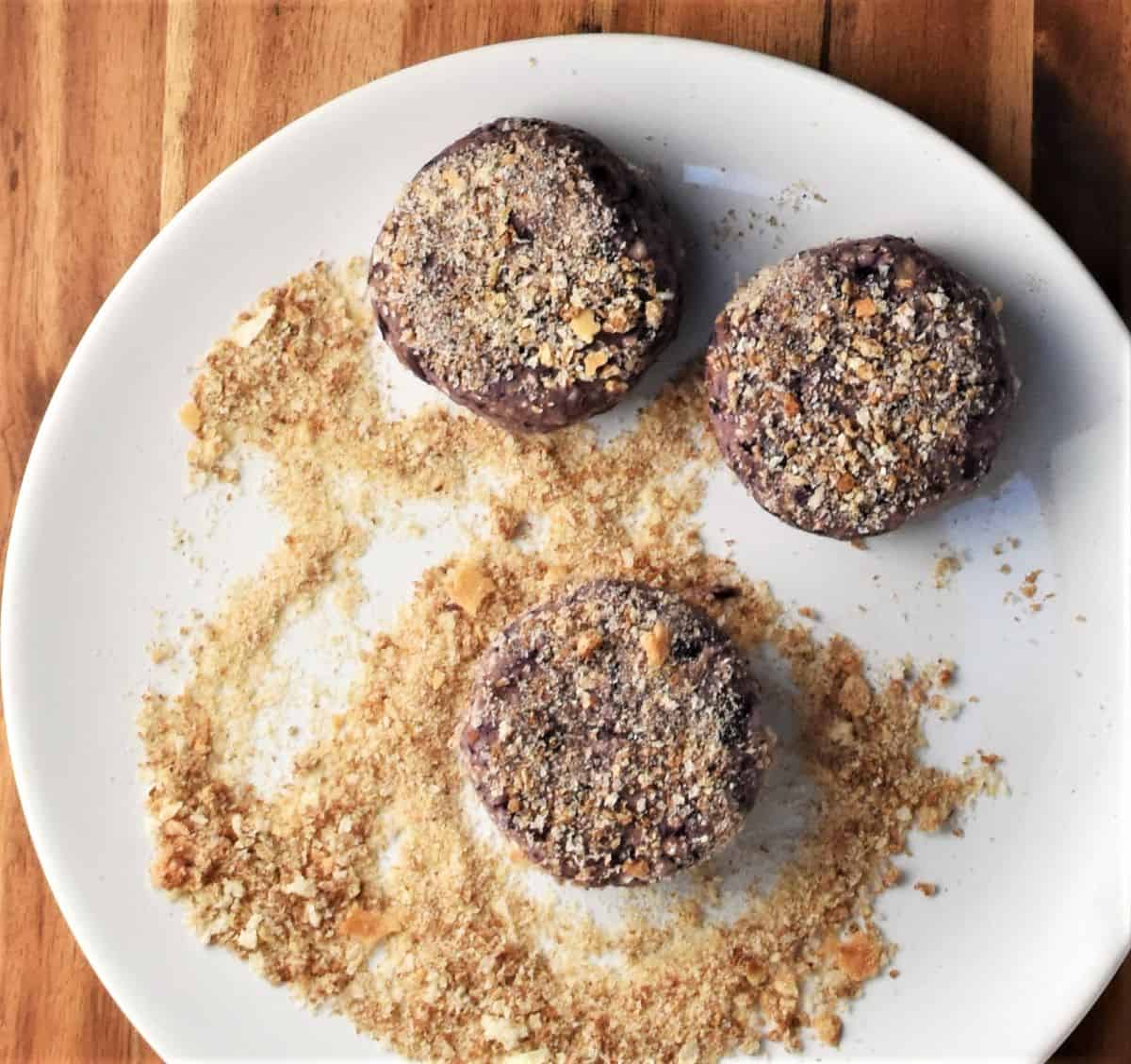 3 cabbage fritters in breadcrumbs on top of plate.