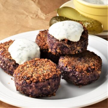 Side view of cabbage patties with yogurt sauce on plate.