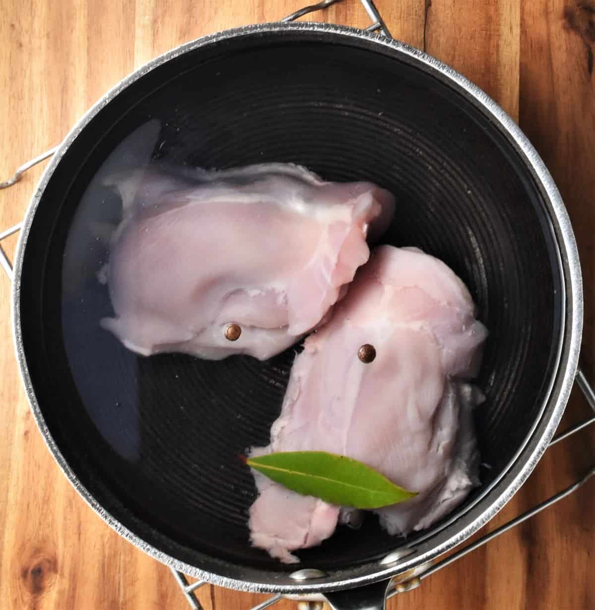 2 skinless chicken thighs and spices in pot of water.