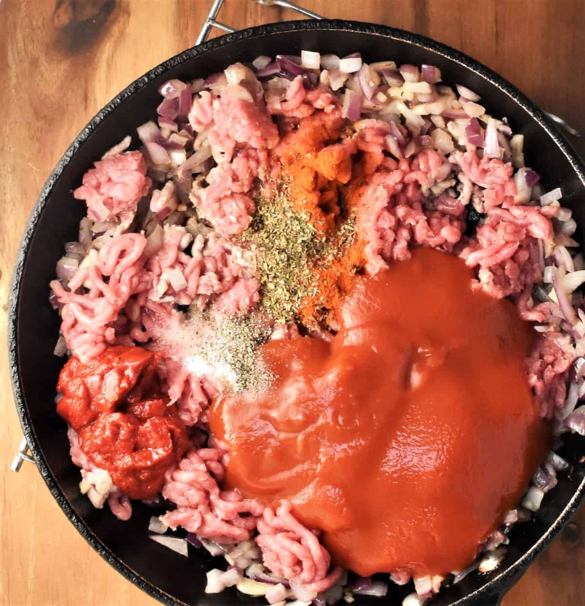 Ground meat, spices and tomato sauce in frying pan.