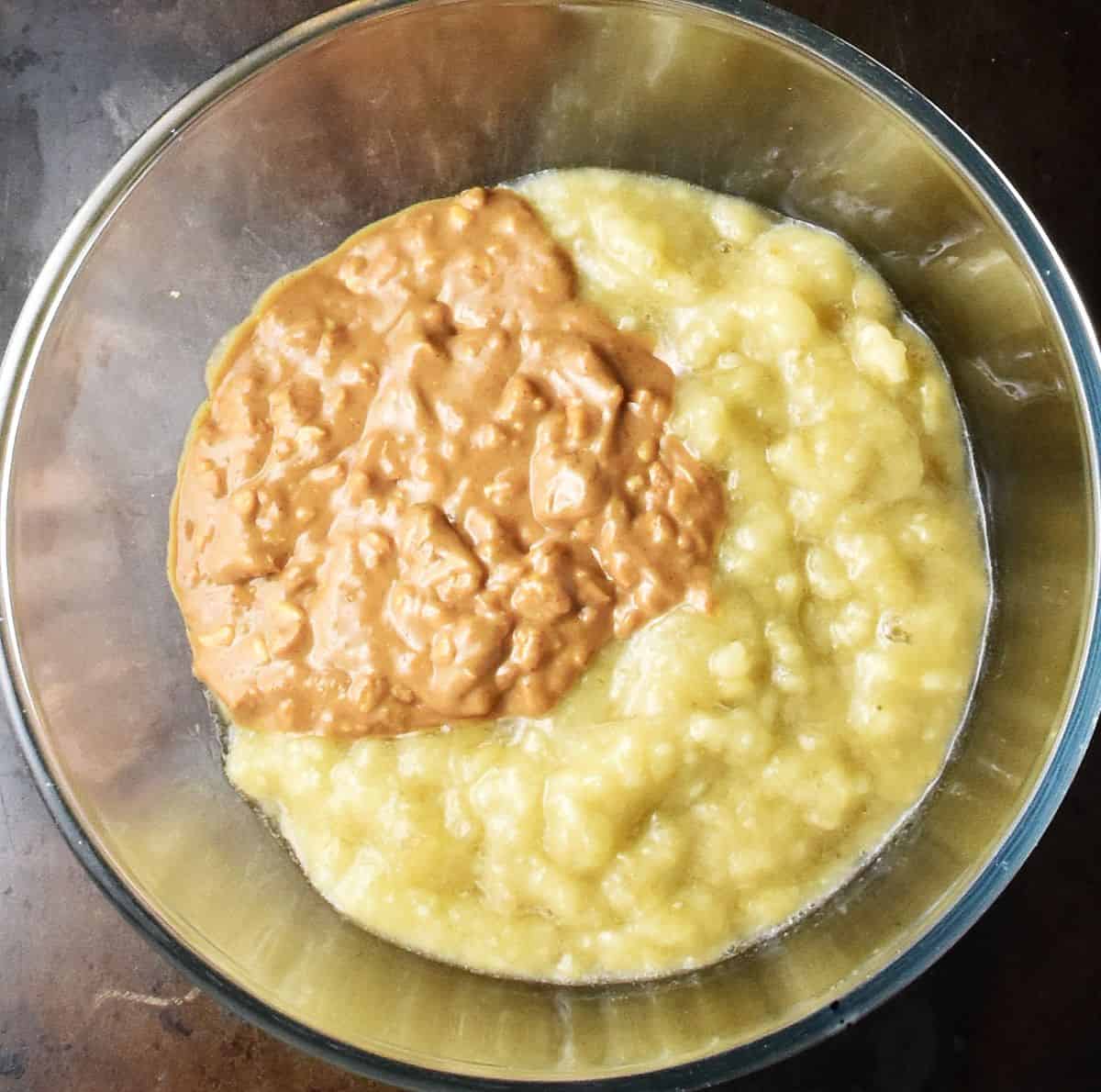 Top down view of crunchy peanut butter and mashed bananas in glass bowl.