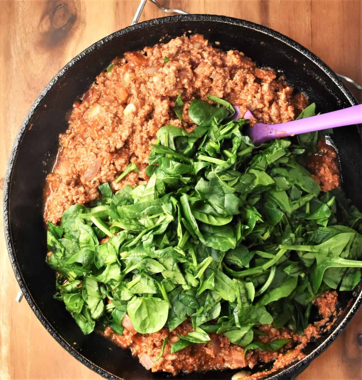 Meat filling with spinach for rice free stuffed peppers in pan.