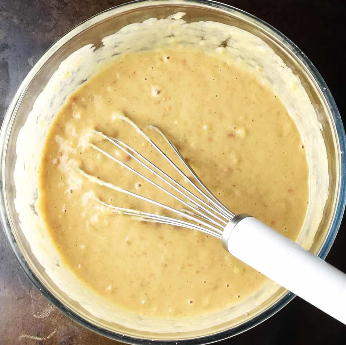 Peanut butter banana muffins wet mixture in glass bowl with whisk.