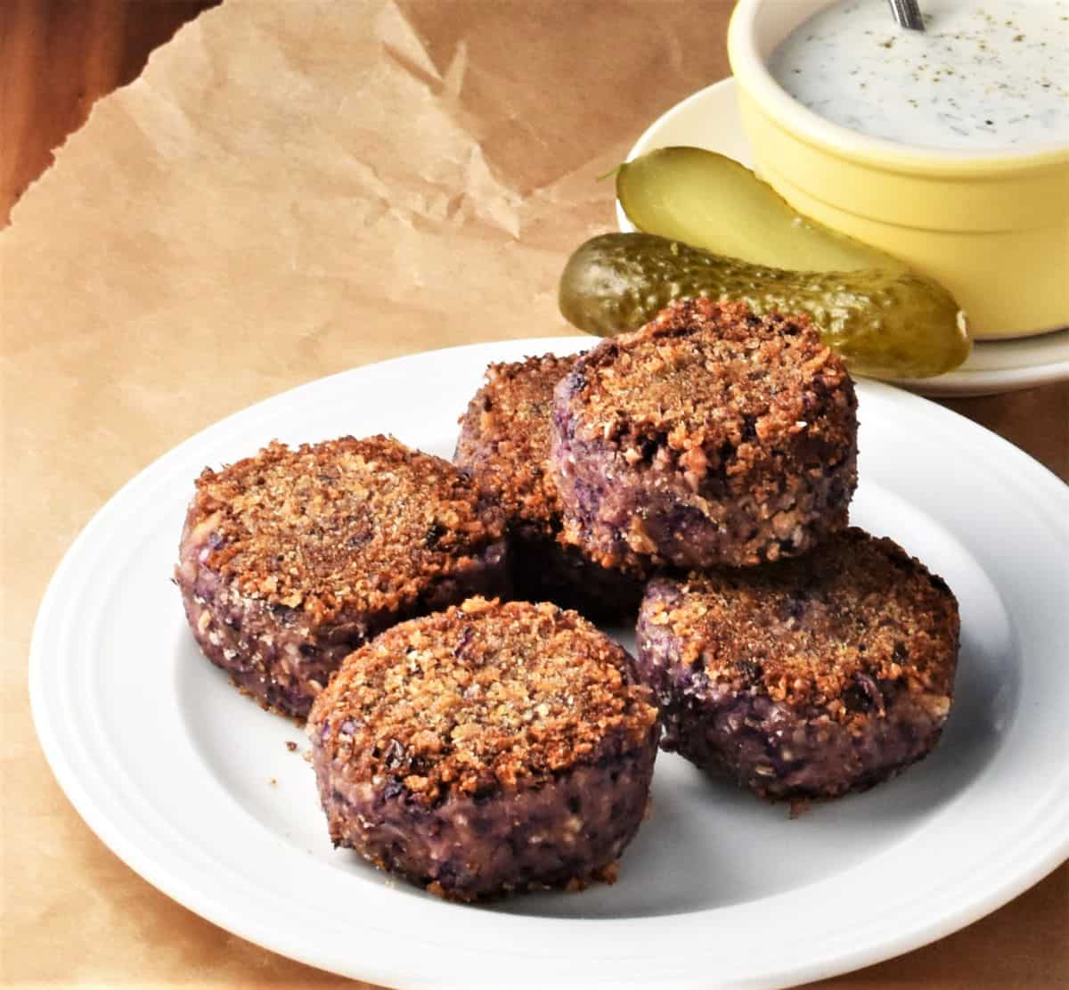 Side view of breaded cabbage patties on white plate.