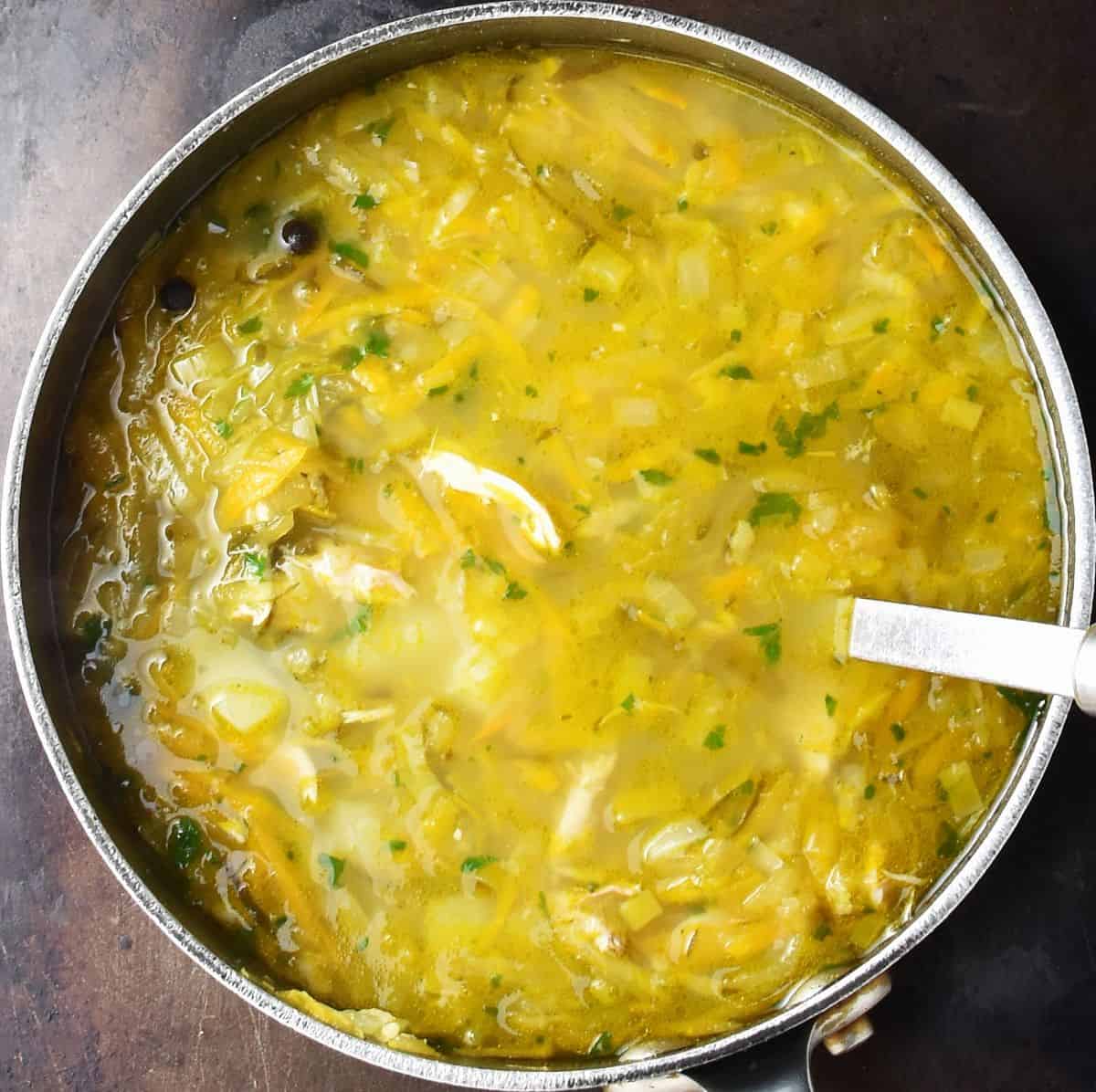 Top down view of Polish dill pickle soup in large pot with ladle.