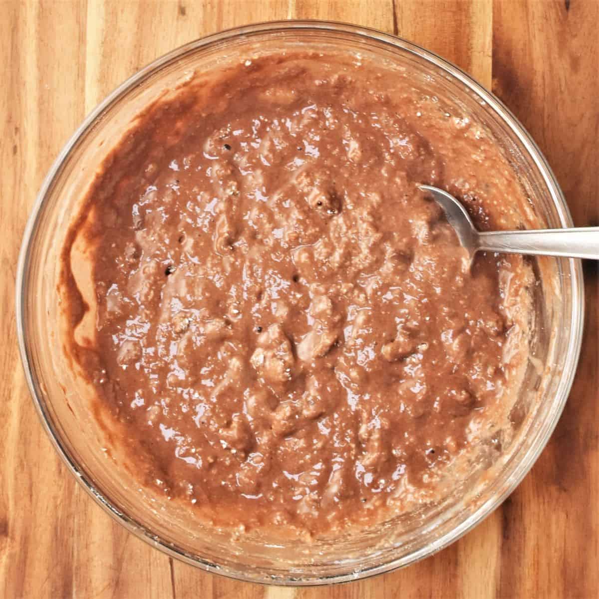 Banana chocolate pancake batter in bowl with spoon.