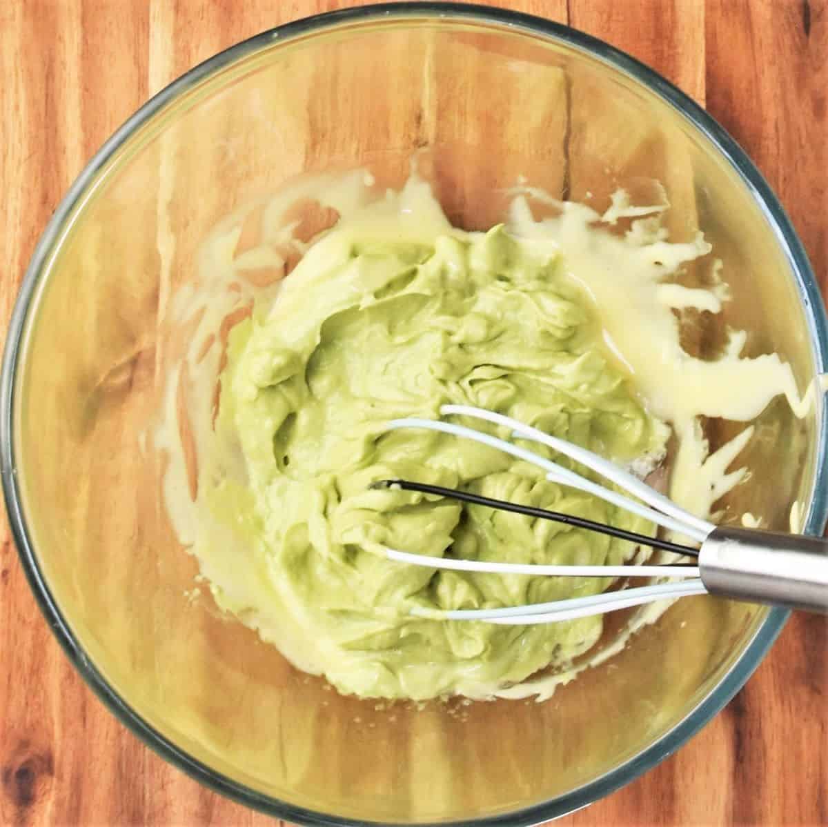 Whisking pureed avocado into mayonnaise.