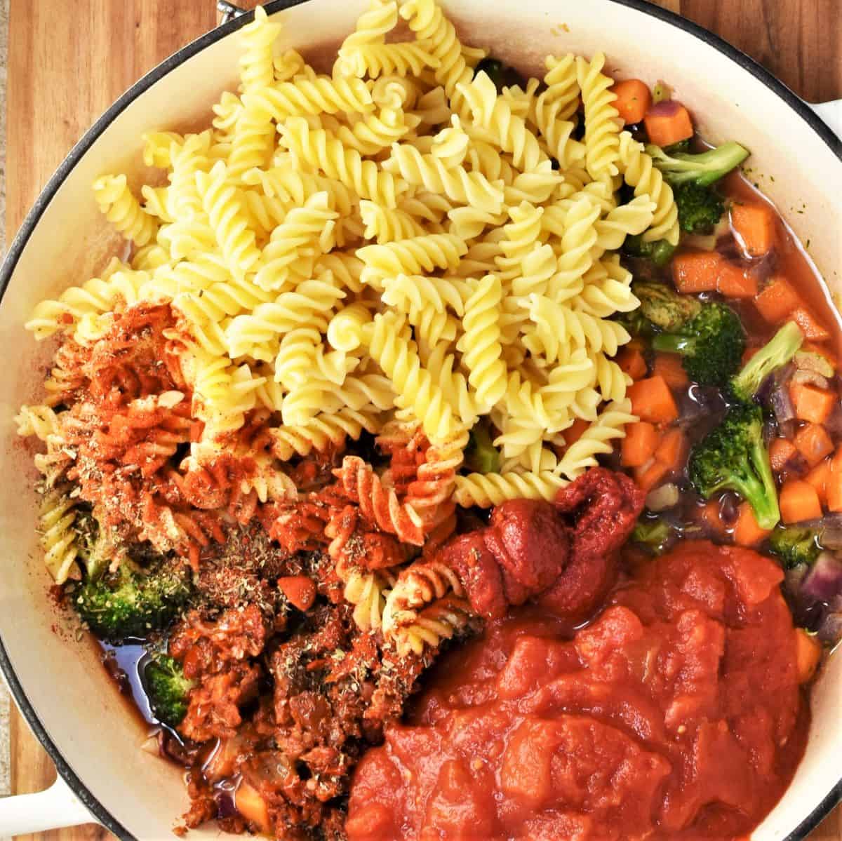 Assembling ground chicken and pasta casserole in large round dish.